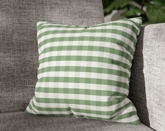 May include: A green and white gingham throw pillow with a square pattern. The pillow is sitting on a gray couch.