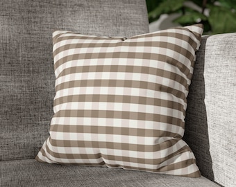 May include: A brown and white checkered throw pillow with a soft, plush texture. The pillow is sitting on a gray couch.