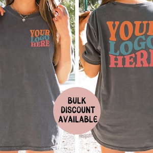 May include: Charcoal gray t-shirt with the text "YOUR LOGO HERE" in orange, teal, and coral. The same text is on the front and back of the shirt. The shirt is a relaxed fit.