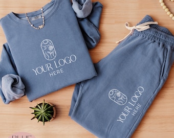 May include: A blue sweatshirt and sweatpants set with a white outline of a rose and the text "YOUR LOGO HERE" on both pieces.