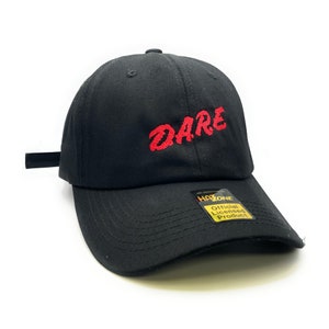 May include: Black baseball cap with a red embroidered "DARE" logo. The cap has a yellow and black "Hat Zone" tag with the text "Official Licensed Product".