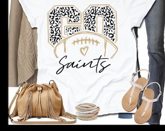 Puede incluir: Camiseta blanca con un diseño "GO Saints" en estampado de leopardo negro y dorado con un balón de fútbol.