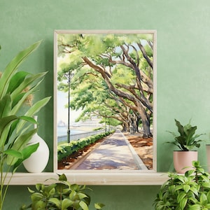 May include: A watercolor painting of a tree-lined path leading to a waterfront. The trees have lush green leaves and the path is shaded by the trees. The painting is framed in a light wood frame.