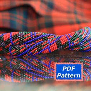 May include: A twisted beaded bracelet in red, blue, and green, with copper-coloured end caps. The image shows a blue rectangle with the text "PDF Pattern". The background is a red and green plaid.
