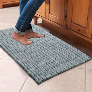 Puede incluir: Una alfombra de cocina azul y verde con un patrón tejido. La alfombra está colocada en un suelo de baldosas delante de un armario de madera.