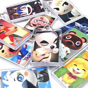 May include: A collection of clear acrylic keychains featuring colorful character designs. Each keychain has a silver metal ring. The keychains showcase various characters from a popular video game, with vibrant illustrations and a glossy finish.
