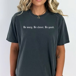Może przedstawiać: Szary t-shirt z nadrukiem "Be wary. Be clever. Be good." w kolorze białym na przodzie.