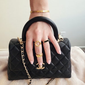 Hand model with chunky rings and black chanel purse