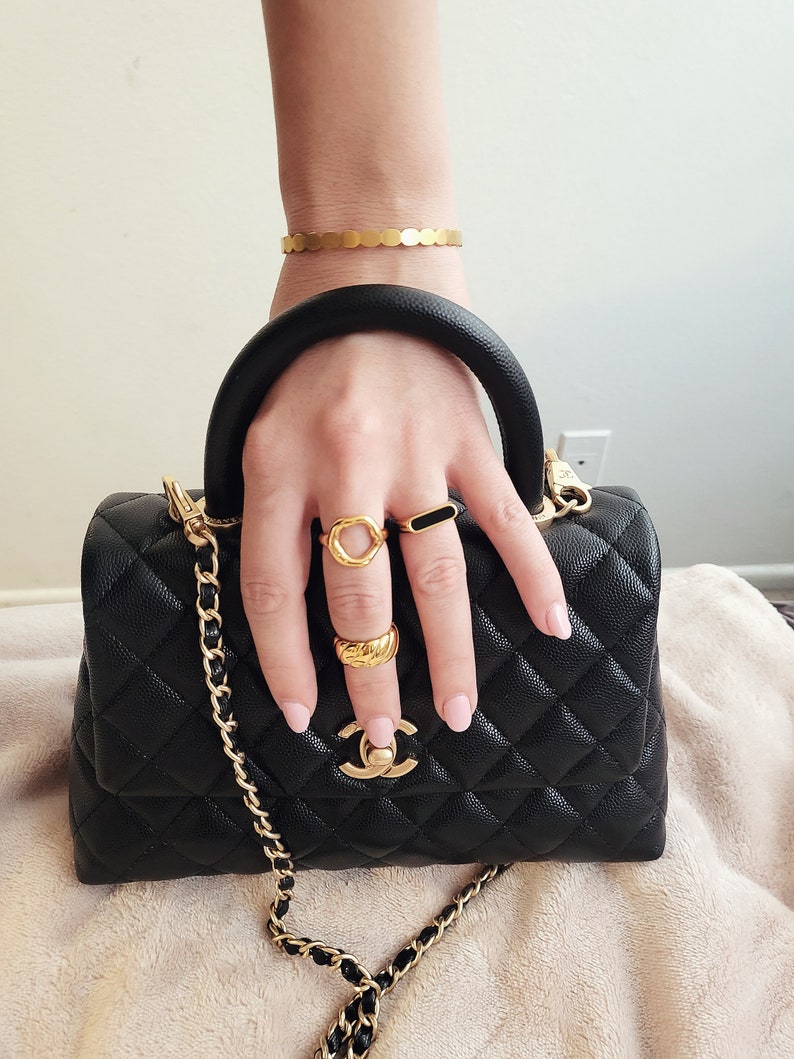 Hand model with chunky rings and black chanel purse