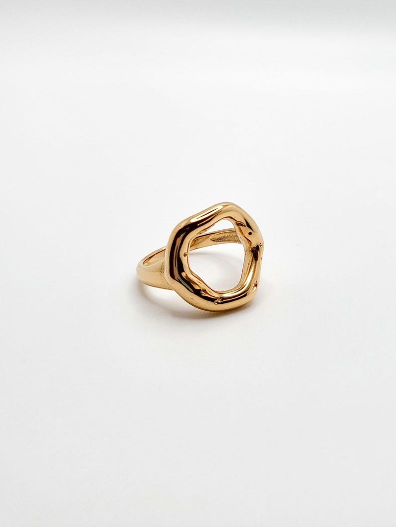 May include: A gold-toned ring with an irregular, organic-shaped open circle design.