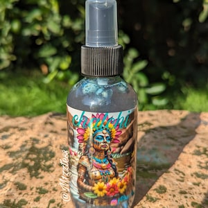 May include: A clear glass bottle with a black spray nozzle and a label featuring a colorful illustration of a woman with a headdress and flowers. The label also includes the text "chichi" and "@Mzzxtess".