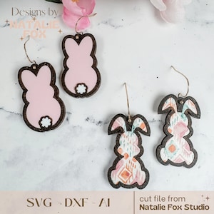 May include: Three pairs of wooden bunny earrings. The first pair is pink with a white tail. The second and third pair are brown with a pink and white patterned design. The earrings are on a white marble surface.  SVG, DXF, AI cut file from Natalie Fox Studio.