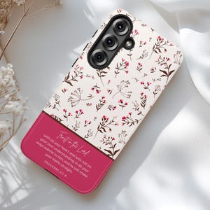 May include: A phone case with a floral pattern and a pink stripe. The case features a cream background with small pink flowers and brown stems. The pink stripe contains the text "Trust in the Lord" and a Bible verse.