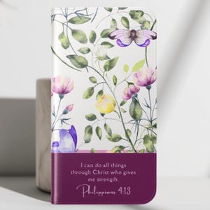 May include: A floral phone case featuring a watercolor design of purple, yellow, and pink flowers, green leaves, and a butterfly on a white background. The bottom section is a deep purple with the text "I can do all things through Christ who gives me strength. Philippians 4:13."