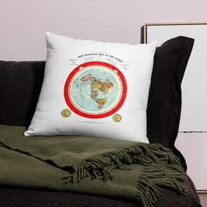 May include: White throw pillow with a vintage-style flat-earth map printed on it. The map is in red, blue, and green colors and shows the continents of the world. The text "New Standard Map of the World" is printed at the top of the map.