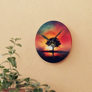 Op de afbeelding: Een ronde klok met een kleurrijk zonsondergangsscene met een silhouet van een boom met zijn reflectie in het water. De wijzers van de klok zijn zwart en wijzen de tijd aan.