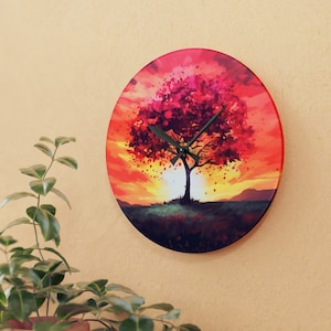 Puede incluir: Un reloj redondo con un fondo de puesta de sol rojo, naranja y amarillo. Un árbol negro con hojas rosas está en el centro de la esfera del reloj. Las manecillas del reloj son negras.