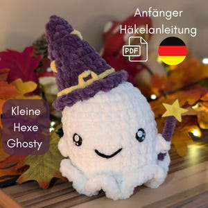 Könnte beinhalten: Ein weißer gehäkelter Geist, der einen lila und gelben Hexenhut mit einem sternförmigen Zauberstab trägt. Der Text "Kleine Hexe Ghosty" befindet sich in der linken unteren Ecke des Bildes. Der Text "Anfänger Häkelanleitung PDF" befindet sich in der rechten oberen Ecke des Bildes.