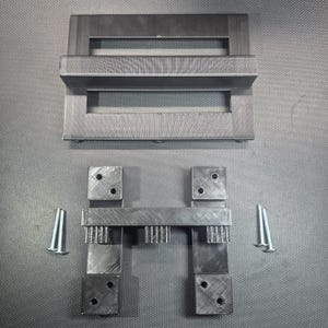 May include: A collection of black 3D-printed parts, comprising two rectangular frames with mesh, two square blocks, and a central structure with vertical supports. Two silver screws are also present.