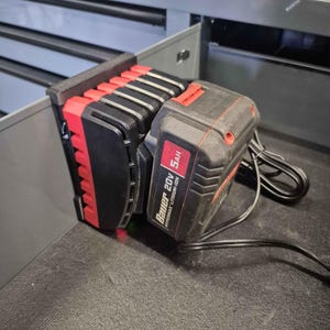 May include: A black and red Bauer 20V Hypermax Lithium-Ion 5Ah battery and charger. The charger is black and red, with a series of slots for multiple batteries. The battery is black with red accents and a white label.