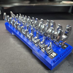 May include: A set of chrome-plated crowfoot wrenches arranged in a blue 3D-printed plastic organizer tray. The tray features the embossed text Icon Crowfoot and individual slots labeled with numerical sizes, including 10, for each metal wrench.