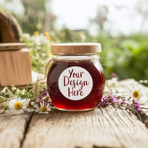 Op de afbeelding: Een glazen pot met een houten deksel gevuld met een donkerrode vloeistof. De pot heeft een wit rond etiket met de tekst "Your Design Here" in maroon.