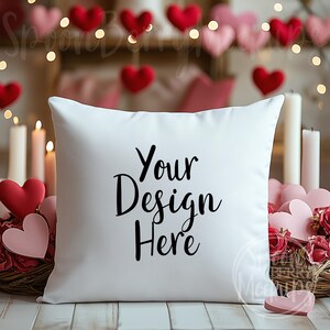 May include: White pillow with the text "Your Design Here" in black cursive font. The pillow is surrounded by pink and red hearts and candles.