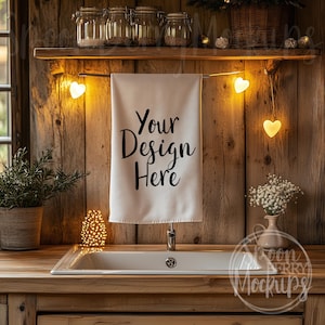 Könnte beinhalten: Ein weißes Küchentuch hängt an einem rustikalen Holzregal mit Lichterketten. Das Tuch trägt den Text "Your Design Here".
