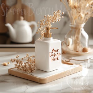 May include: White ceramic soap dispenser with a gold pump and the text "Your Design Here" on a wooden tray with dried flowers.