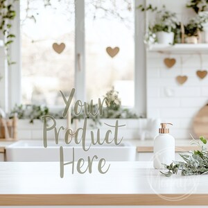 Puede incluir: Encimera blanca con una botella de jabón blanca con bomba y una rama de vegetación. El texto "Your Product Here" está escrito en el fondo.