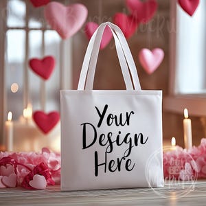 May include: White tote bag with black text that says "Your Design Here" against a background of pink hearts and candles.