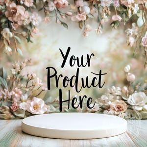 Può includere: Un piedistallo rotondo bianco si trova su una superficie di legno chiaro davanti a uno sfondo floreale. Il testo "Your Product Here" è scritto in lettere corsive nere.