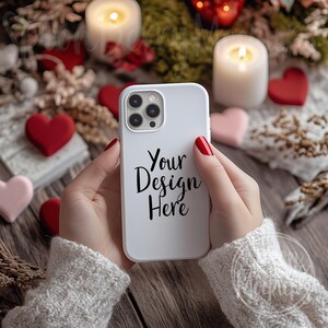 May include: White iPhone case with a black camera lens and the text "Your Design Here" on a white background. The case is being held by a person with red nail polish.