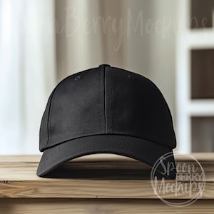 May include: A black baseball cap with a curved brim. The cap is sitting on a wooden surface.