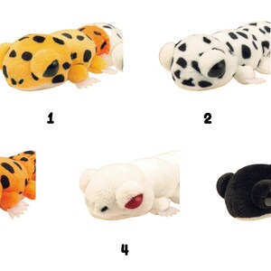May include: A collection of five plush toy animals in a row. The toys include a leopard, a Dalmatian, an orange lizard, a white bear, and a black bear. Each toy has a unique design and color scheme.
