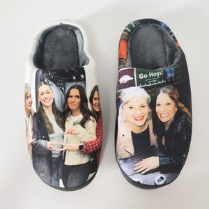 May include: A pair of plush, indoor slippers. One slipper features a group of women, the other has a different group of women with the text "Go Hogs!". Both slippers have a soft, gray interior.