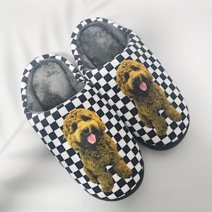 Peut inclure: Une paire de pantoufles à carreaux noirs et blancs. Chaque pantoufle présente un motif de chien brun avec la langue sortie. L'intérieur des pantoufles est en matière grise douce.