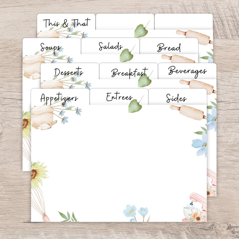 Op de afbeelding: Witte receptkaartsplitsers met bloemen- en bakthema-illustraties. De tabbladen zijn gelabeld met categorie&euml;n als 'Soepen', 'Salades' en 'Desserts'. Het ontwerp bevat aquarel zonnebloemen, deegrollers en mixers.