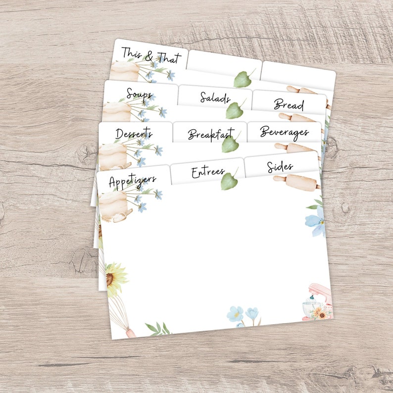 Op de afbeelding: Witte receptkaartsplitsers met aquarel illustraties met bloemen en keukenthema's. De tabbladen zijn gelabeld met categorie&euml;n zoals "Soepen", "Salades" en "Desserts". Het ontwerp bevat blauwe bloemen, deegrollers en een mixer.