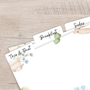Op de afbeelding: Witte papieren verdelers met de woorden "Breakfast", "Sides" en "This & That" erop gedrukt. De verdelers hebben aquarel illustraties van een deegroller, bloemen en een theepot. De achtergrond is een lichte houtnerf.