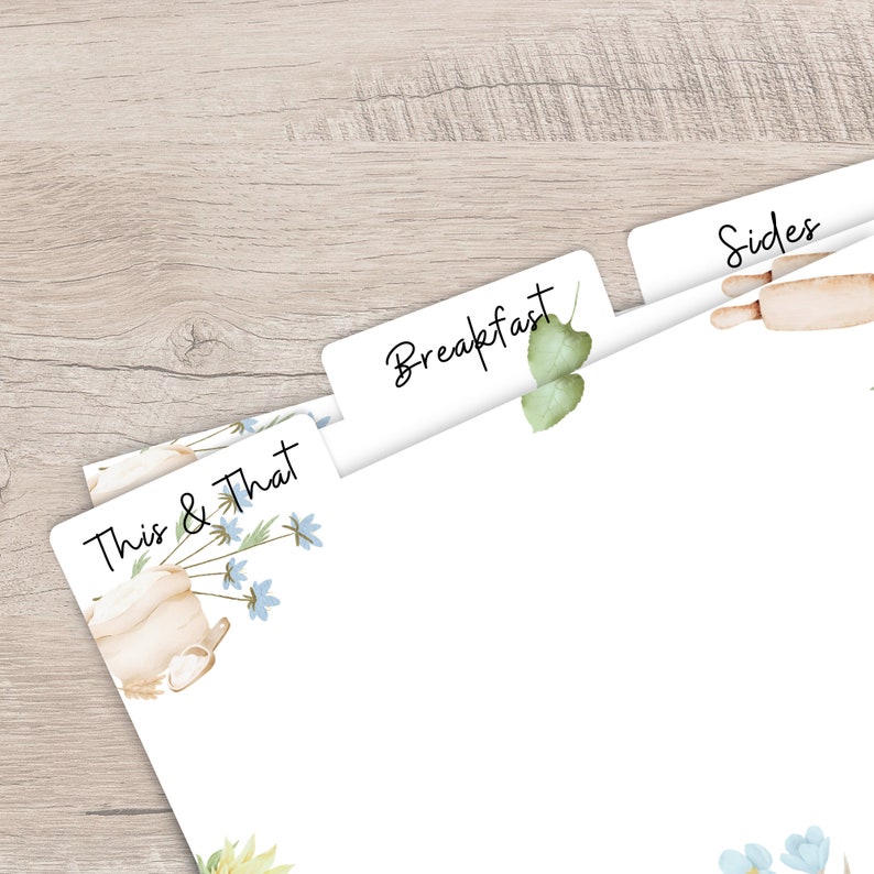 Op de afbeelding: Witte papieren verdelers met de woorden "Breakfast", "Sides" en "This & That" erop gedrukt. De verdelers hebben aquarel illustraties van een deegroller, bloemen en een theepot. De achtergrond is een lichte houtnerf.