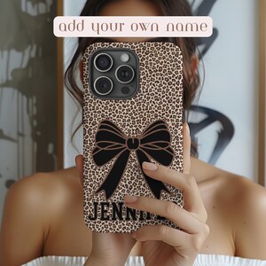 May include: A brown and black leopard print phone case with a black bow and the name "JENNI" printed on the bottom.