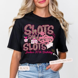 May include: Black t-shirt with a pink and gold design featuring the words "Slots and Slots" with a Las Vegas casino sign and dice. The text "Jackie's 30th Birthday" is also included.