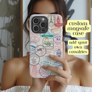 May include: White phone case with a colorful design of passport stamps from various countries, including Canada, Mexico, London, Athens, and more. The text "custom magsafe case add your own countries" is printed on the right side of the image.