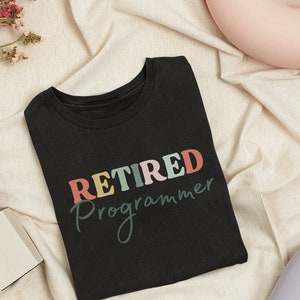 May include: Black t-shirt with the text "RETIRED Programmer" in colorful letters on a white background.