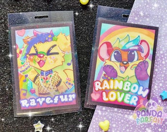 May include: Two colorful cartoon animal character badge holders with rainbow backgrounds. The left badge holder features a yellow furry character with a purple and blue mohawk, wearing a black mesh top and colorful jewelry. The text "ravefur" is printed on the badge. The right badge holder features a brown furry character with a blue and green mohawk, wearing a rainbow shirt. The text "RAINBOW LOVER" is printed on the badge.