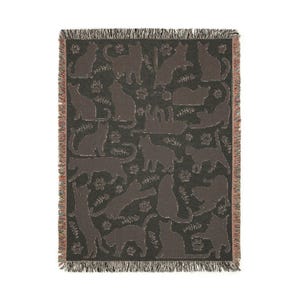 May include: A woven throw blanket featuring a repeating pattern of cat silhouettes in various poses, paw prints, and fish bones. The cats are a dark brown color against a dark gray background. The blanket has a fringed edge.