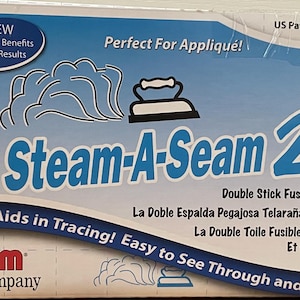 May include: A blue and white box for Steam-A-Seam 2, a double-stick fusible web for appliqué. The box features text in English and Spanish, a floral design, and an image of a child.