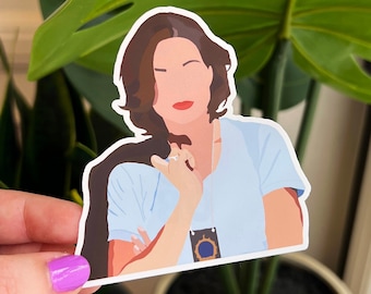 May include: A sticker featuring a cartoon illustration of a woman with brown hair wearing a blue shirt and a badge. She is holding her hand to her chin and looking to the side.