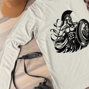 K&ouml;nnte beinhalten: Ein Langarmshirt mit einem schwarz-wei&szlig;en Grafikdruck eines spartanischen Kriegers, der eine Lanze und einen Schild h&auml;lt. Der Krieger tr&auml;gt einen Helm und einen Umhang.